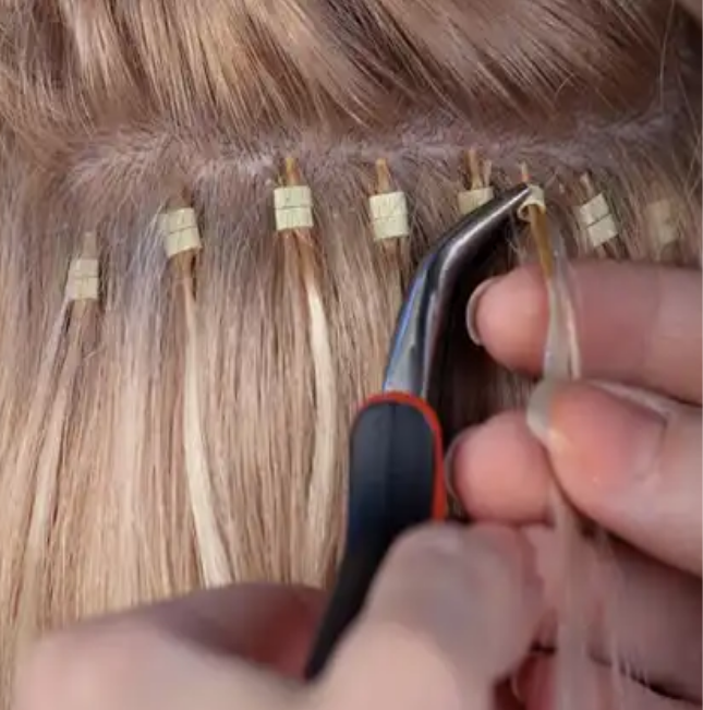 Stylist installing a microlink extension with a micro bead