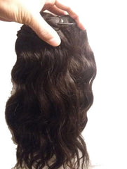 Hand holding wavy dark brown hair bundle to buy North Indian raw hair online from Chandra Hair